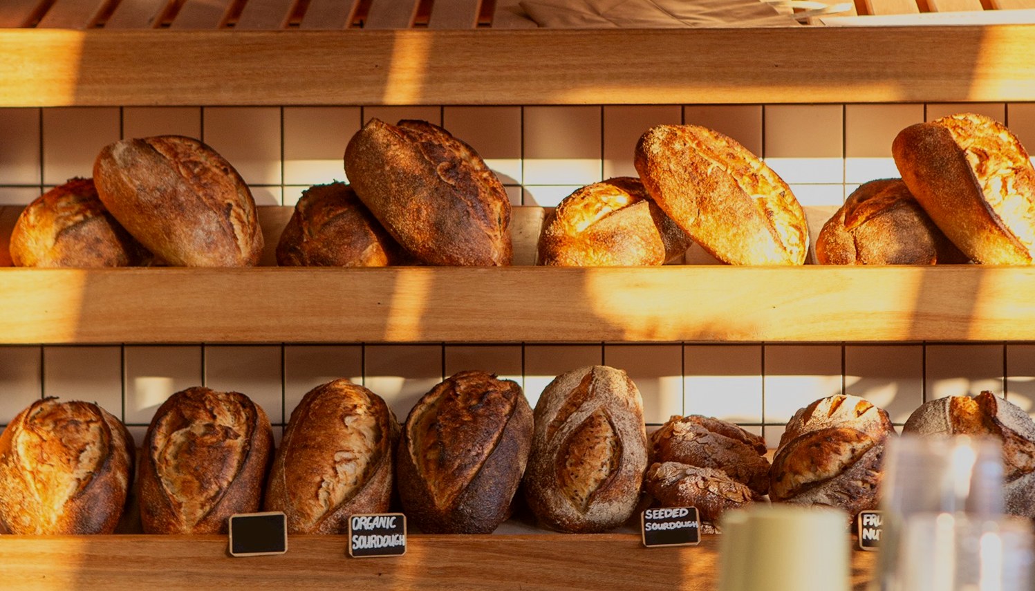 Sourdough loaves on timber shelves at Tucker, lit by low morning sun
