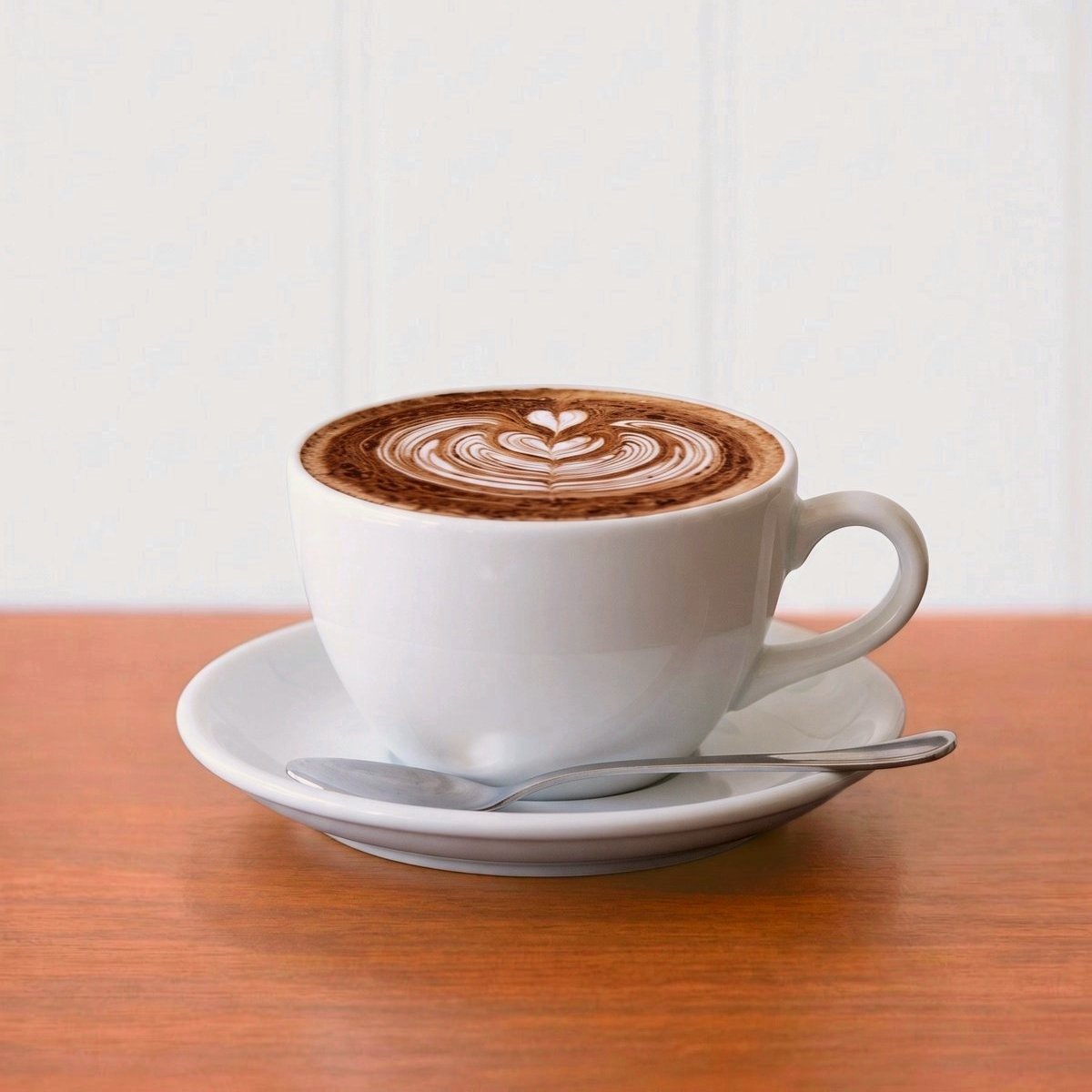 Cappuccino with rosetta latte art and chocolate dusting in a white cup and saucer