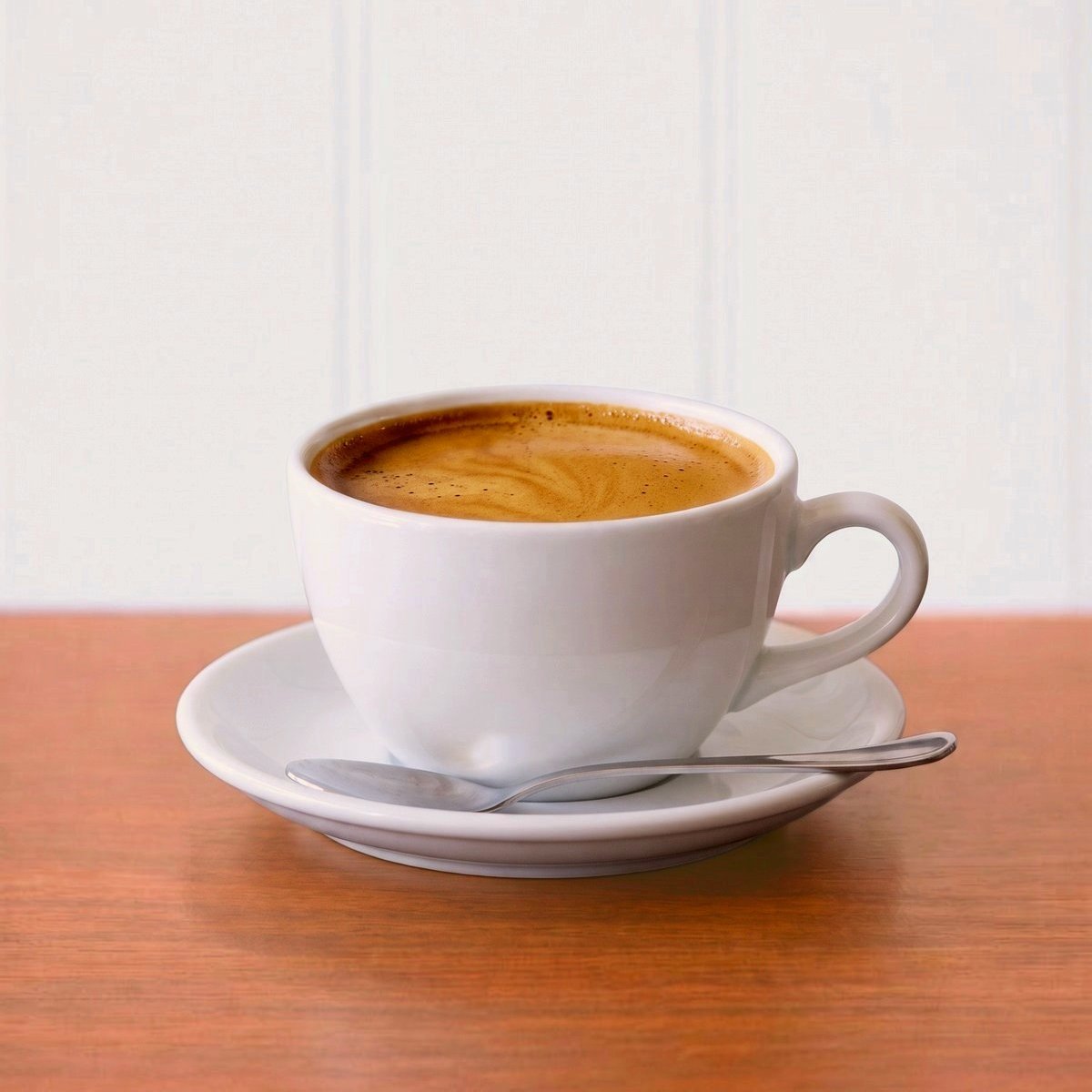 Long black with golden crema in a white cup and saucer